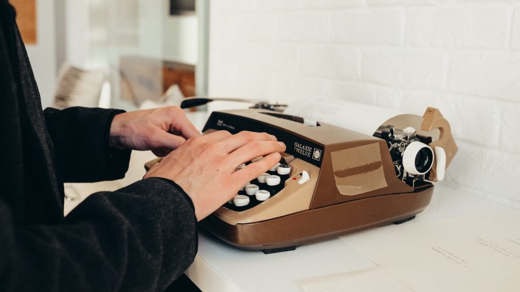 An author at work, typing on a vintage typewriter, capturing the essence of creative writing.